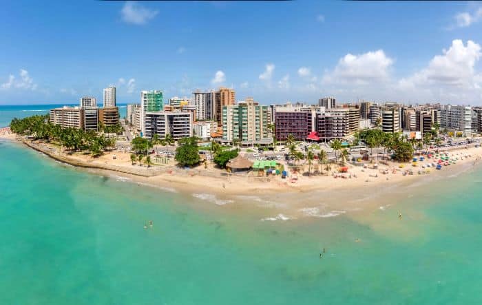 Vista aérea de la playa de Ponta Verde en Maceió, con el mar turquesa y edificios al fondo.