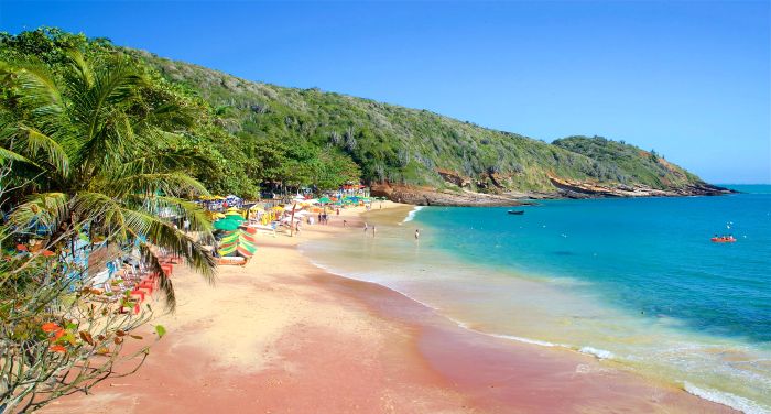 Playa João Fernandes en Búzios: ensenada en semicírculo con aguas esmeralda, arena fina y colinas cubiertas de vegetación al fondo.