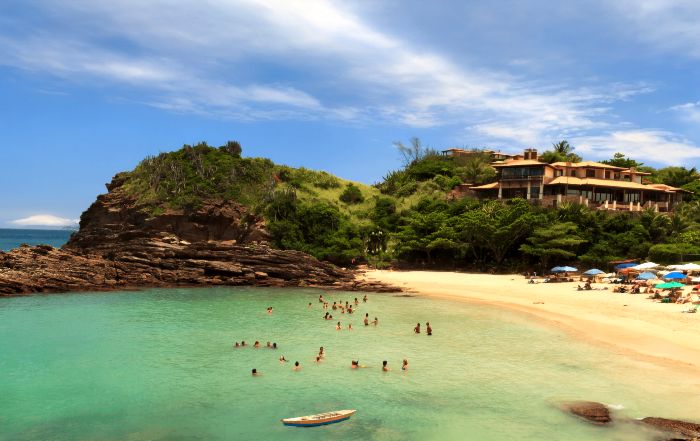 Pequeña cala de la Praia da Ferradurinha en Búzios, rodeada de rocas y vegetación, con aguas cristalinas y calmadas.