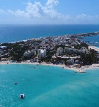 Vista aérea de Isla Mujeres capturada por dron, con playas de arena blanca, aguas turquesas y vegetación tropical
