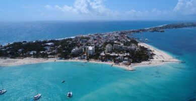 Vista aérea de Isla Mujeres capturada por dron, con playas de arena blanca, aguas turquesas y vegetación tropical