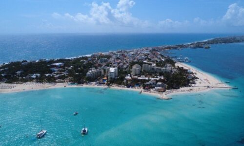 Vista aérea de Isla Mujeres capturada por dron, con playas de arena blanca, aguas turquesas y vegetación tropical